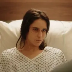 Una mujer en bata de hospital mira fijamente, quizás buscando respuestas sobre el hombre del laberinto final explicado.