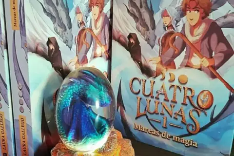 Un huevo de dragón de cristal y libros de "Cuatro Lunas" de Laura Gallego, un ejemplo de literatura fantástica española.