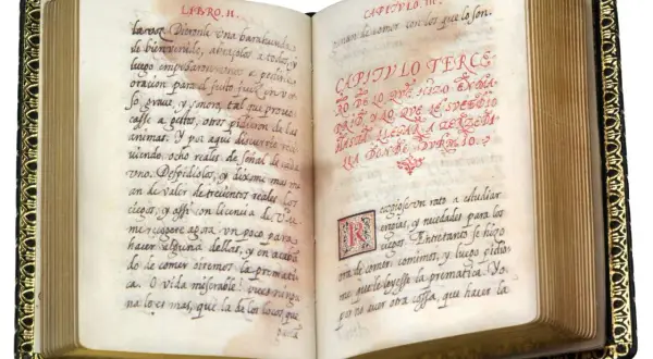 Libro antiguo abierto con escritura a mano en español. Se lee "historia de la vida del buscon" en el texto.