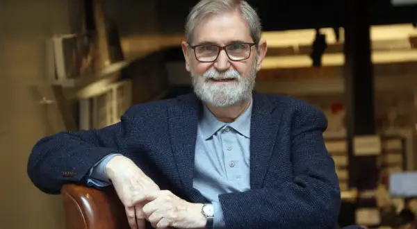 Un hombre mayor con gafas y barba blanca, vestido con chaqueta y polo, evoca la figura de escritores catalanes del siglo XX.