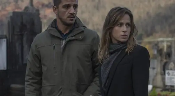 Un hombre y una mujer en un cementerio, con aspecto preocupado. Podría ser una escena del resumen de "Ofrenda a la tormenta".