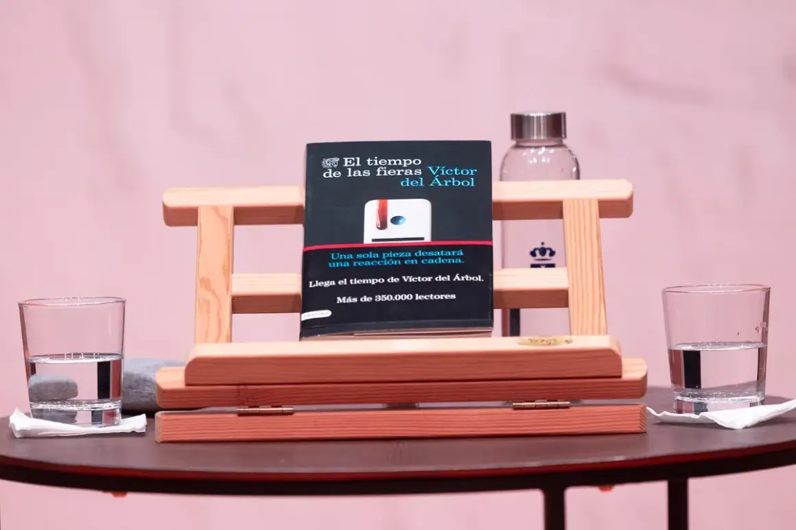 Libro "El tiempo de las fieras" de Víctor del Árbol, con dos vasos de agua y un fondo rosa.