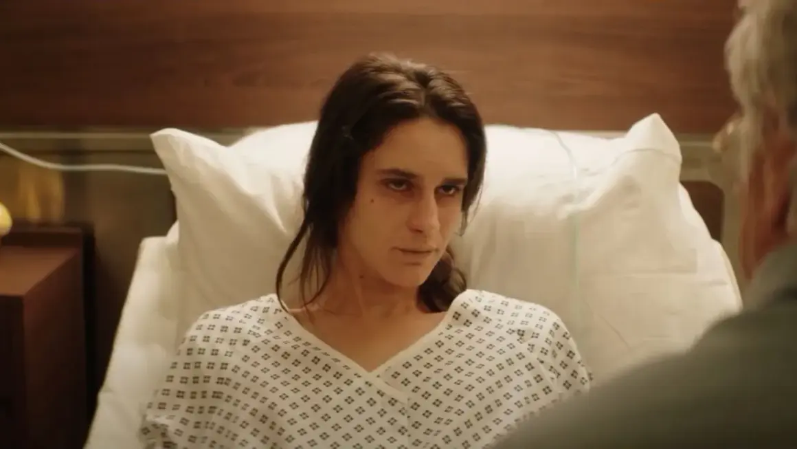 Una mujer en bata de hospital mira fijamente, quizás buscando respuestas sobre el hombre del laberinto final explicado.