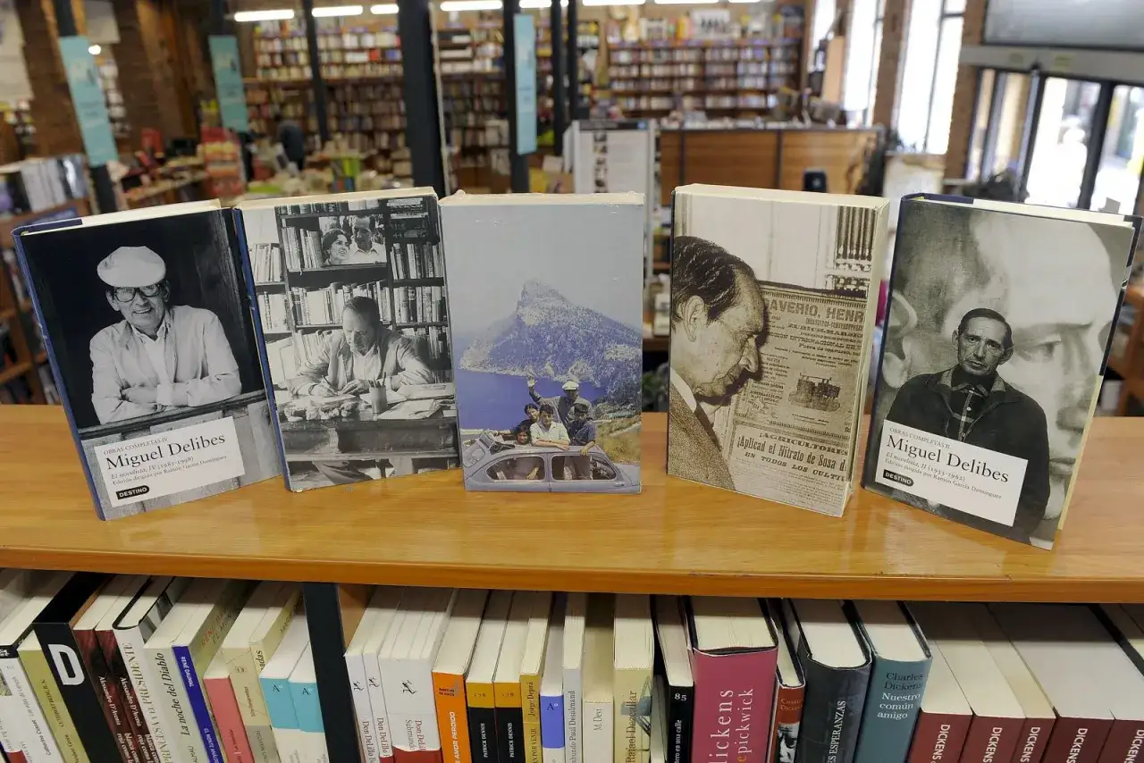 Estanterías llenas de libros, destacando varias ediciones de las obras de Miguel Delibes, con retratos del autor en las portadas.