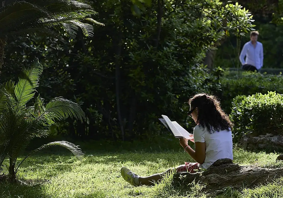 Jove adolescent llegint llibres en valenci&agrave; en un jard&iacute; verd i assolellat.