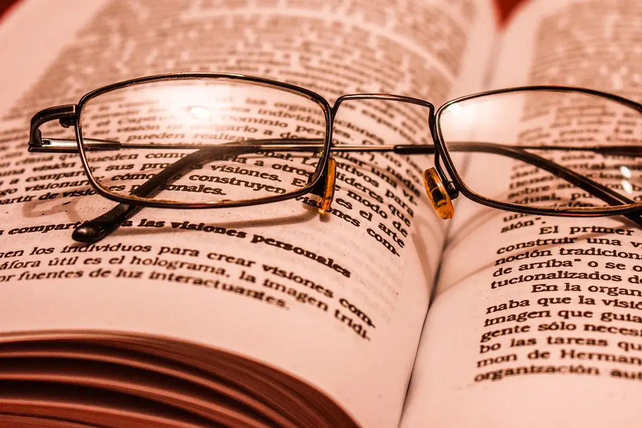Unas gafas descansan sobre un libro abierto, invitando a sumergirse en libros de filosofía para empezar y explorar nuevas ideas.
