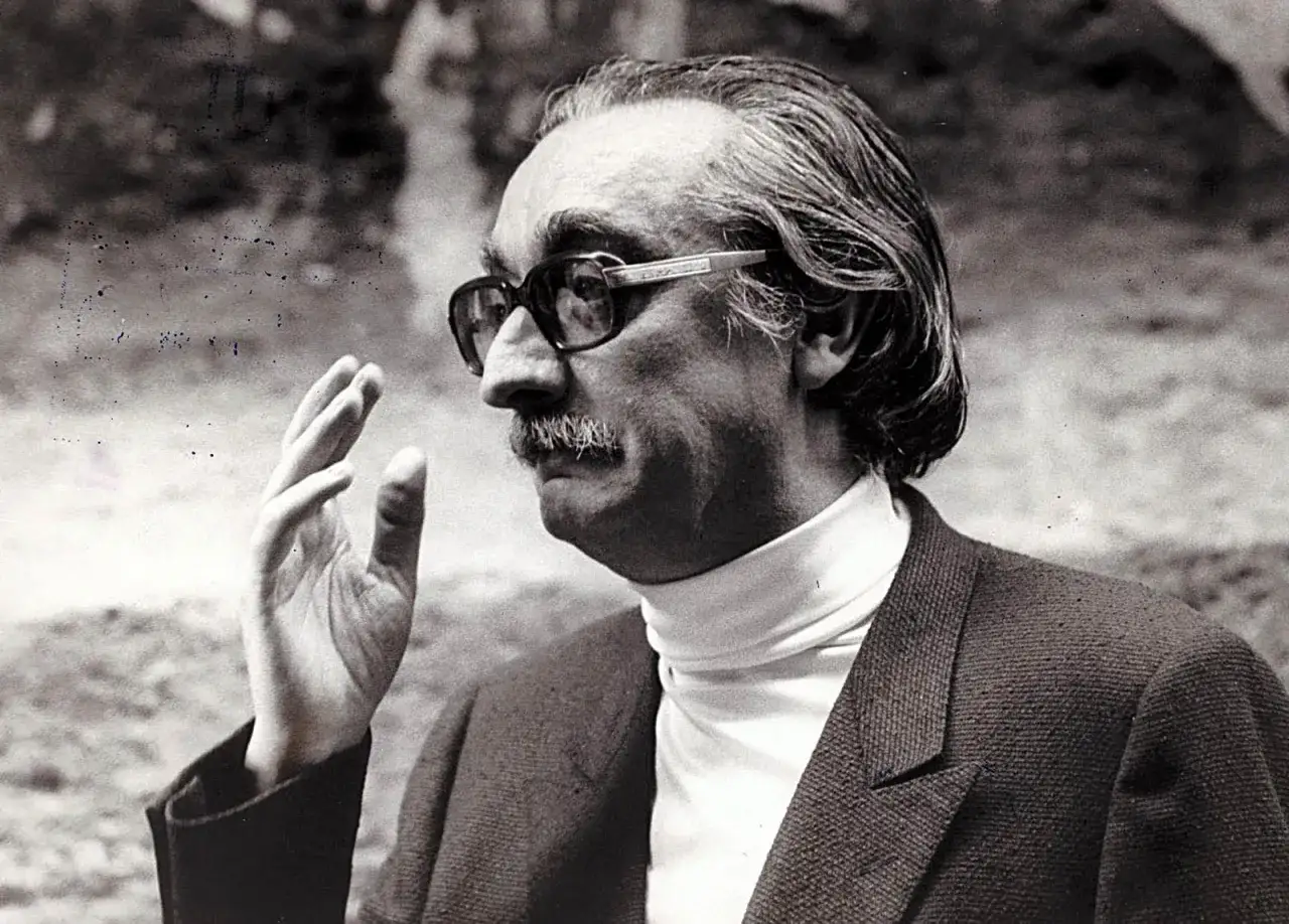 Retrato de un hombre con gafas y bigote, posible figura entre los escritores catalanes del siglo XX, con la mano alzada.