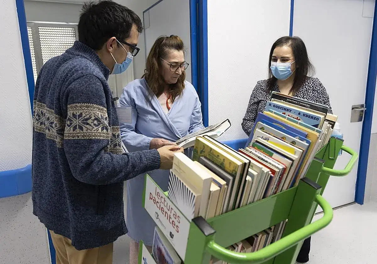 Personas seleccionan libros de un carrito, buscando historias reales para leer.