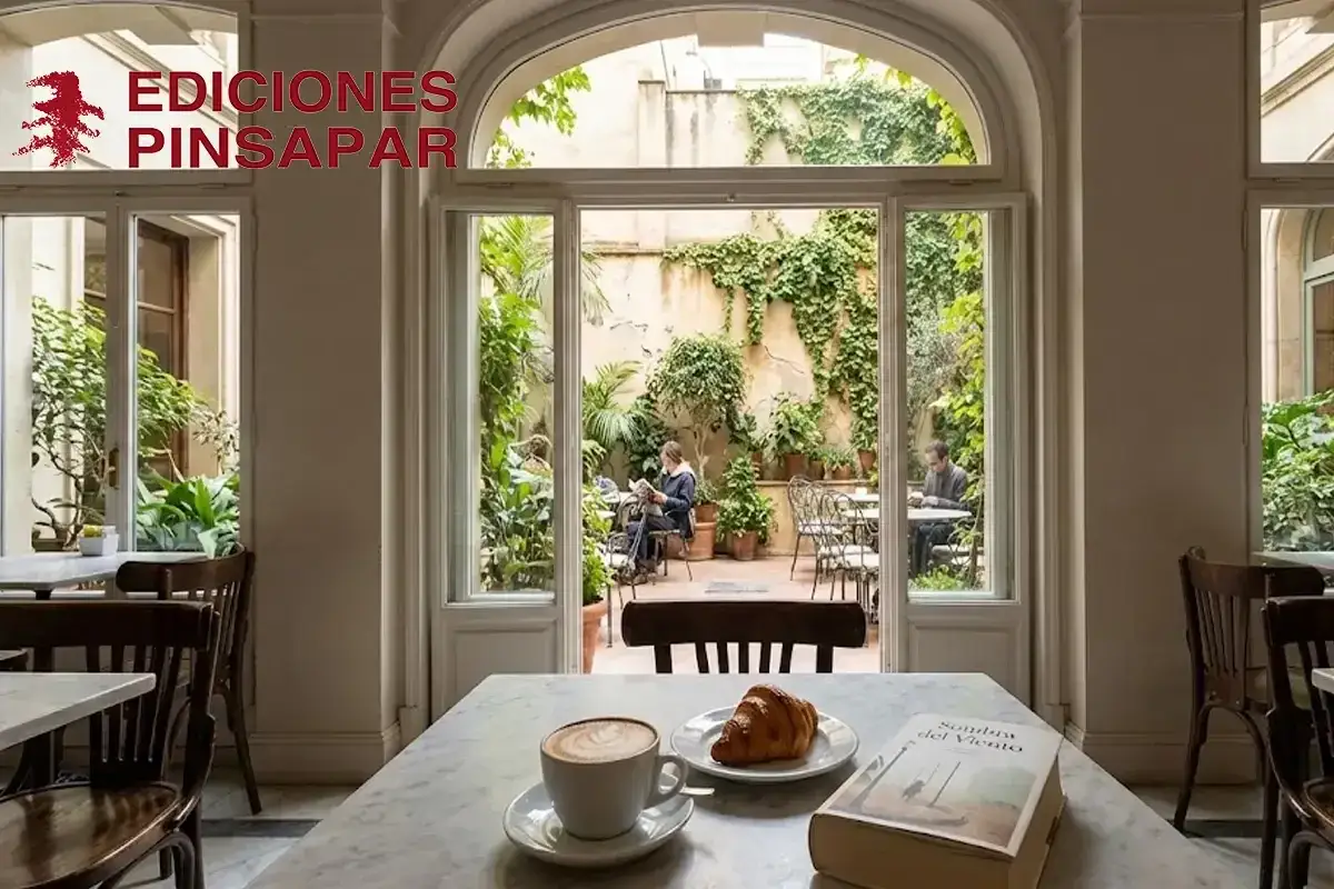 Caf&eacute; con patio interior verde. Una taza de caf&eacute;, un croissant y un libro de novelas optimistas esperan en la mesa.