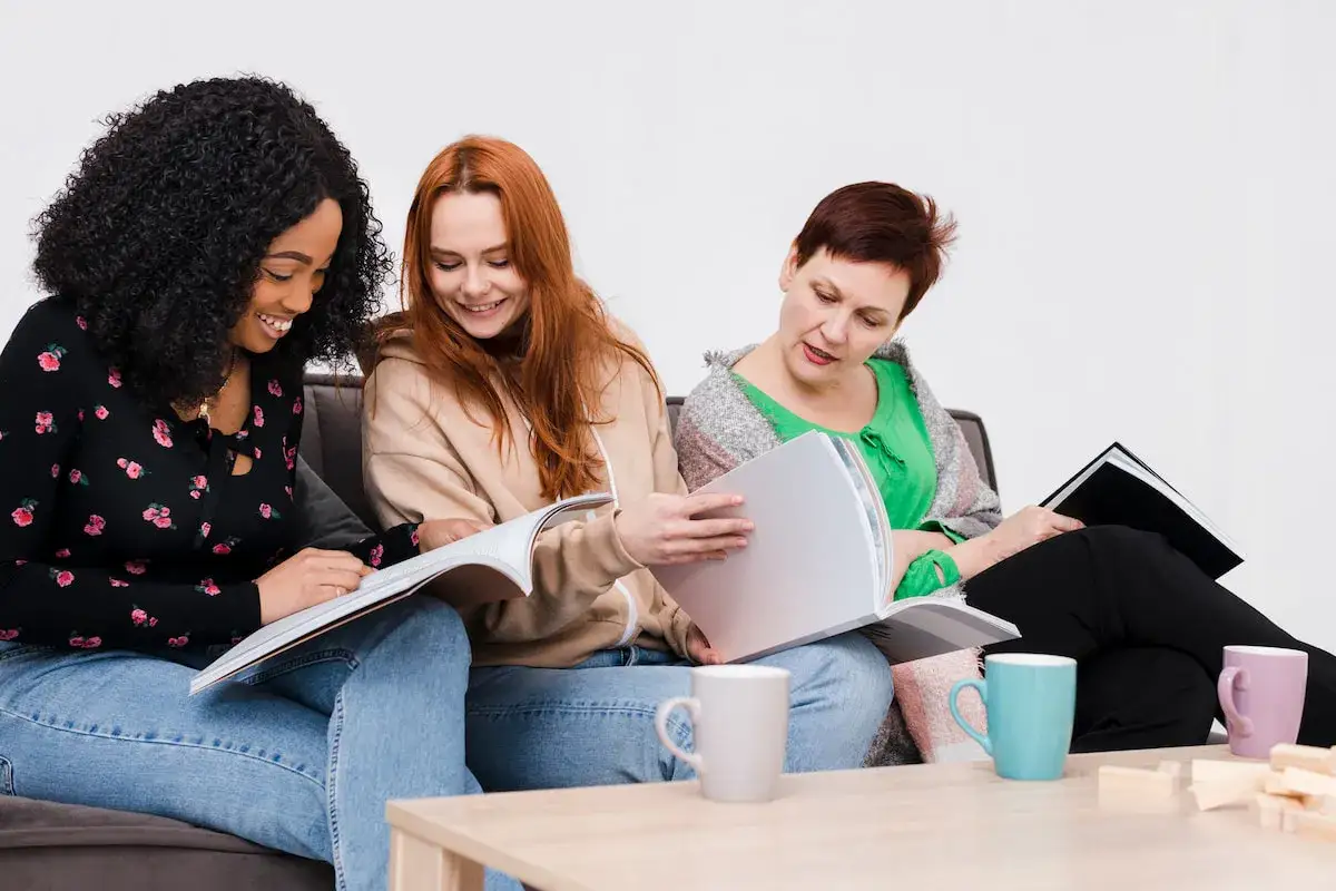 Tres mujeres comparten un momento de lectura, intercambiando recomendaciones para su club de lectura.