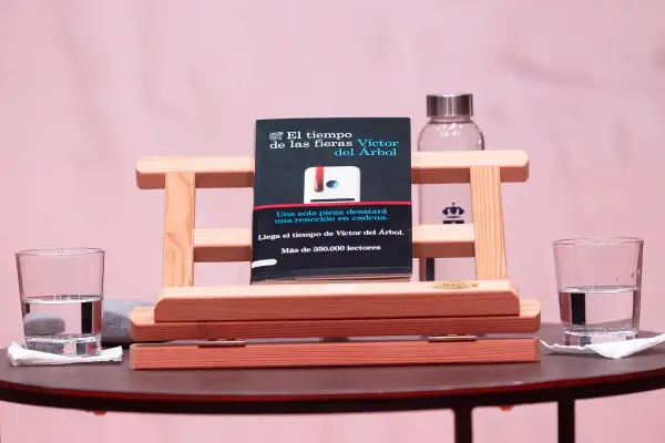 Libro "El tiempo de las fieras" de Víctor del Árbol, con dos vasos de agua y un fondo rosa.