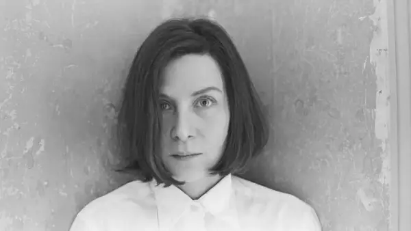 Retrato en blanco y negro de Donna Tart, con su mirada intensa y cabello corto, vestida con una camisa blanca.