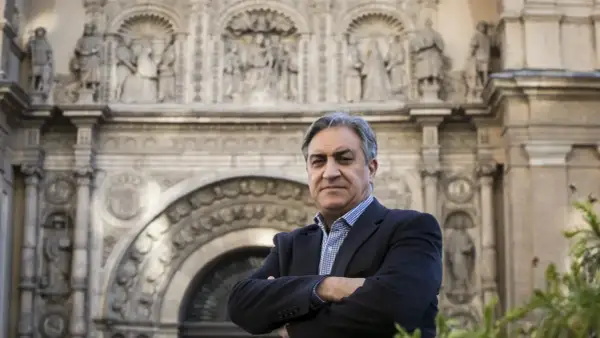 Un hombre con traje posa frente a un edificio histórico, evocando la tradición de los escritores aragoneses actuales.